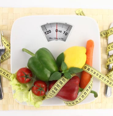 Vegetables and tape measure on scales